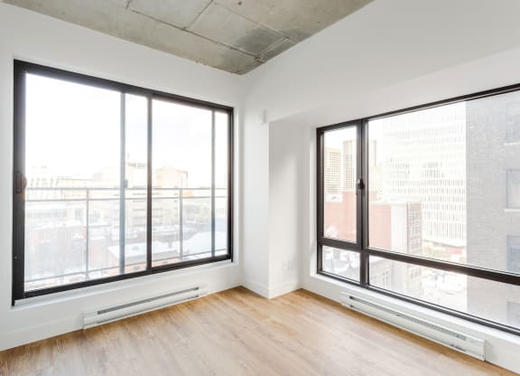 a living room with large windows and wood floors and a city view