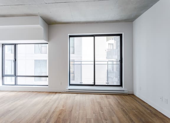 an empty living room with a large window and wooden floors