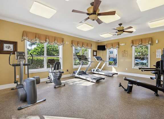 a home gym with exercise machines and a ceiling fan