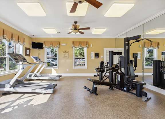 a home gym with exercise equipment and a ceiling fan