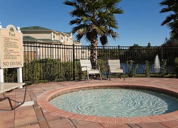 a hot tub with chairs and palm trees in the background