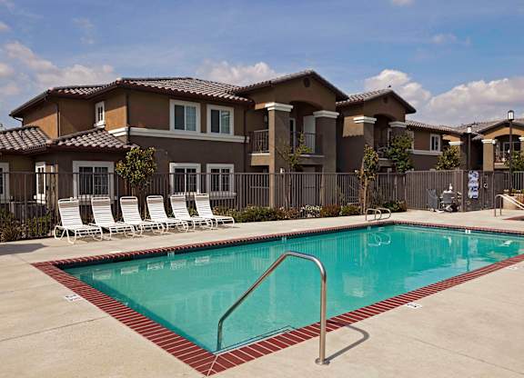 a swimming pool with chaise lounge chairs and a building in the background