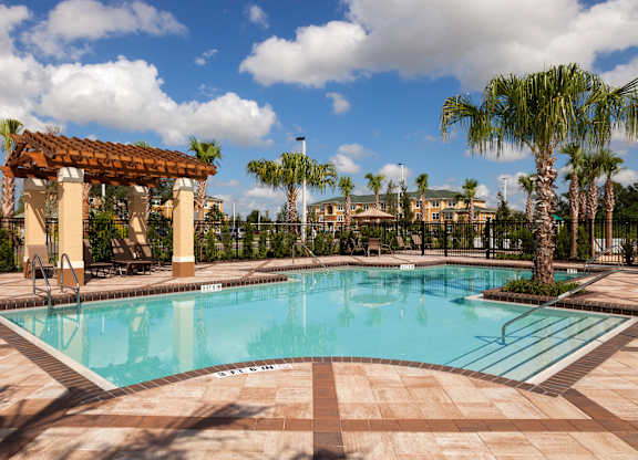 a large swimming pool with a gazebo and palm trees in the background