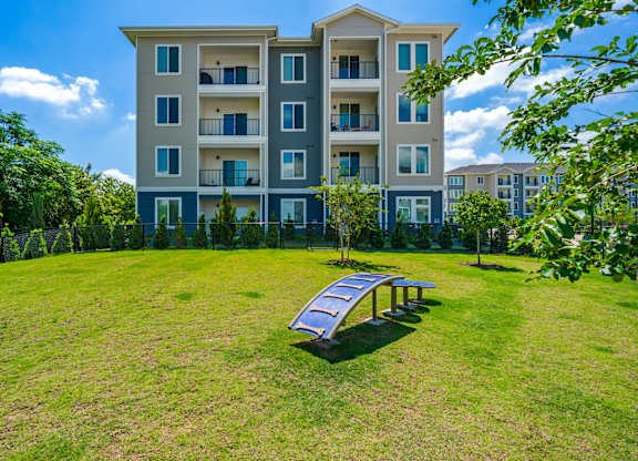 A large grassy area in front of a multi-story apartment building.