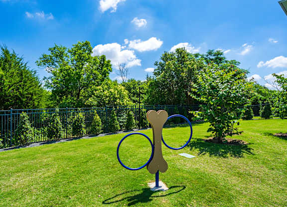 A dog bone sculpture is in the middle of a grassy area.