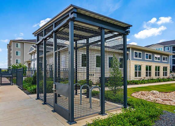 A black metal fence encloses a small building with a glass front.