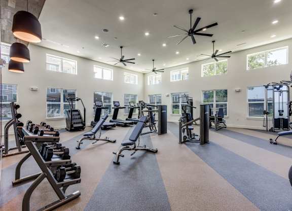 A spacious gym with a variety of equipment and a ceiling fan.