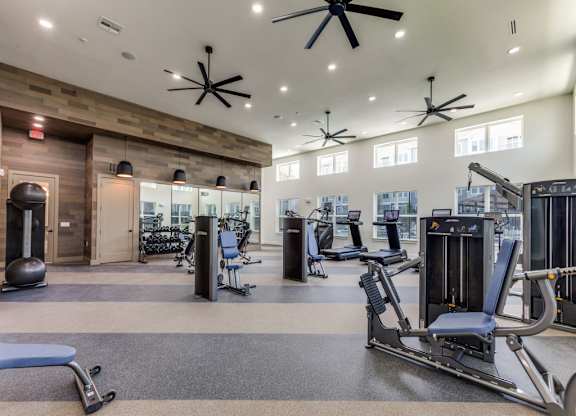 A gym with a variety of equipment including treadmills, weights, and exercise machines.