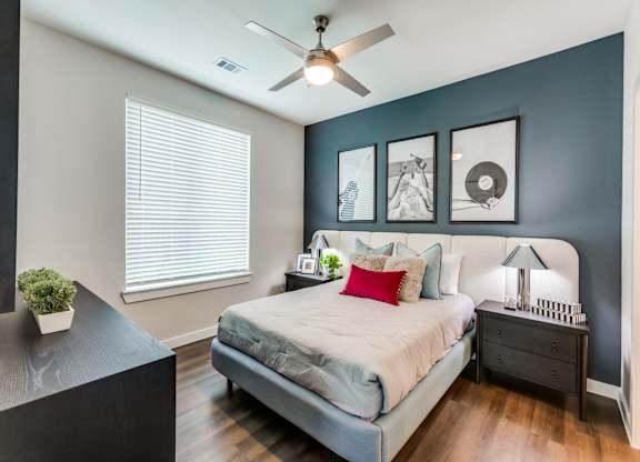 A bedroom with a bed, nightstand, and a ceiling fan.