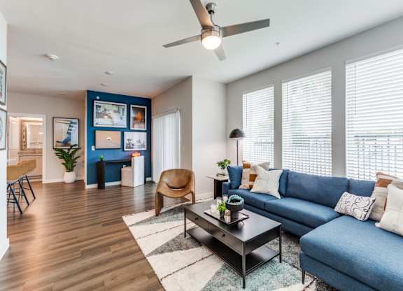 A living room with a blue couch and a wooden floor.