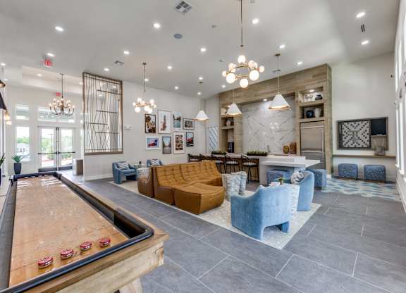 A billiard table is in the middle of a room with a blue couch and a yellow couch.