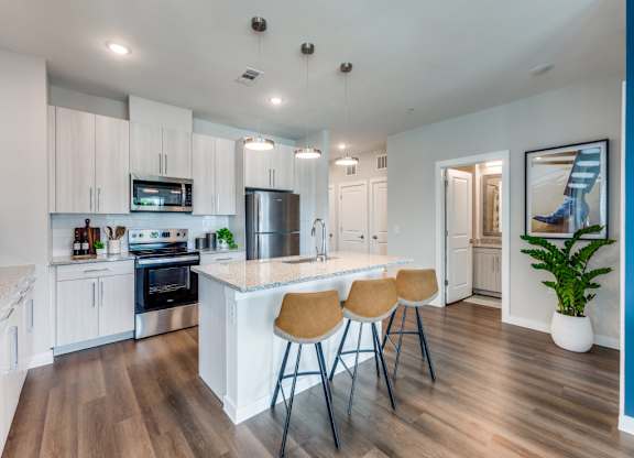 A kitchen with white cabinets and a wooden floor.