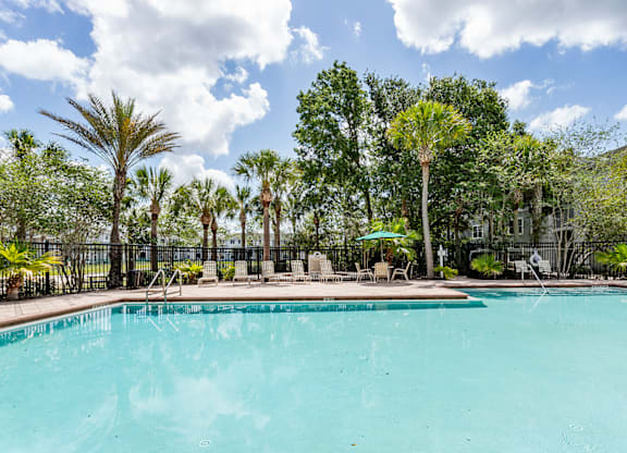 A large swimming pool surrounded by trees and a fence.