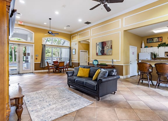 A living room with a black couch and a rug.