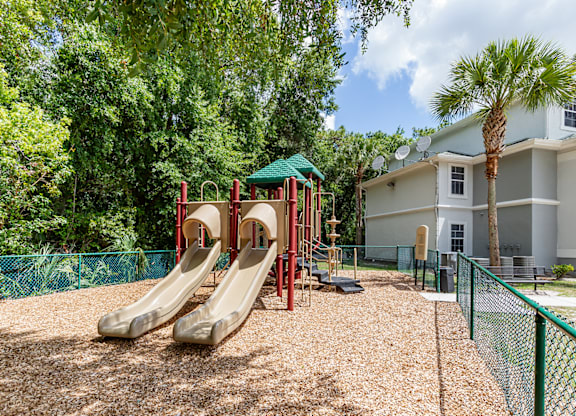 A playground with a red slide and a green roofed structure.