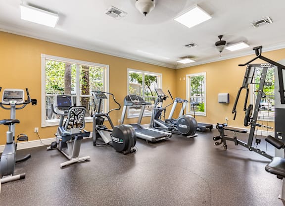 A spacious gym with various exercise equipment and a ceiling fan.