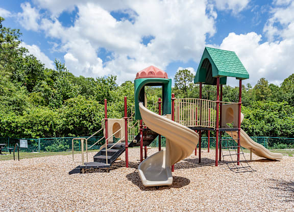 A playground with a slide, a climbing frame and a roundabout.