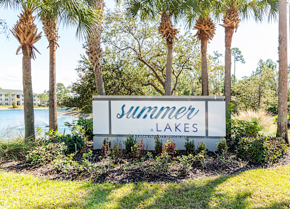 A sign that says "Summer Lakes" is in front of some trees.