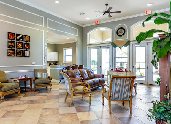 A living room with a brown sofa and wooden chairs.