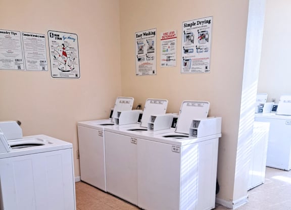 A laundromat with washers and dryers and instructions on the wall.