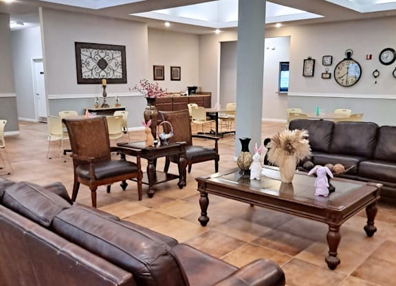 A living room with brown leather furniture and a large clock on the wall.