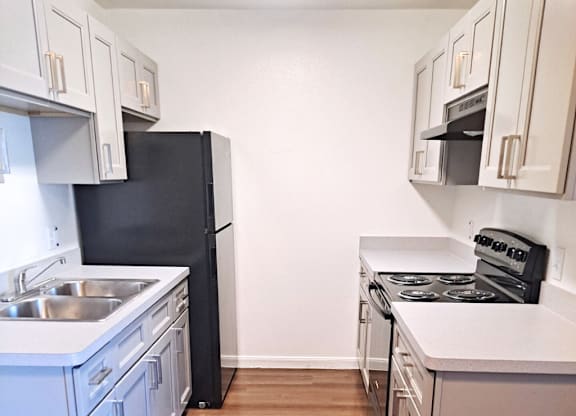 A kitchen with a black refrigerator and white cabinets.