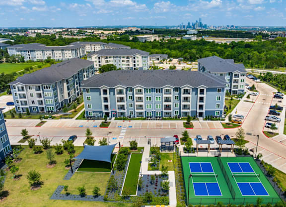A large building with a tennis court in front of it.