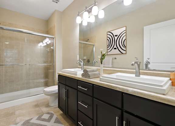 Bathroom with glass shower and double sink at The Amalfi Clearwater Apartments