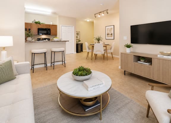 A modern living room with a white couch, a coffee table, and a flat-screen TV.