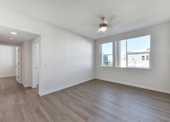 A spacious room with a ceiling fan and large windows.