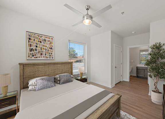 A bedroom with a bed, a ceiling fan, and a painting on the wall.