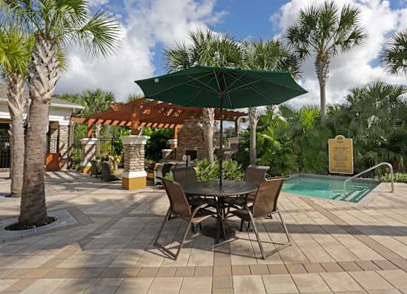 A patio with a table and chairs and a pool in the background.