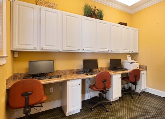 A yellow wall with a white desk and chairs.