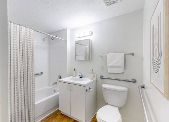 A white bathroom with a toilet, sink, and shower.