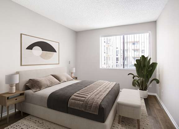A bedroom with a bed, nightstand, and a plant.