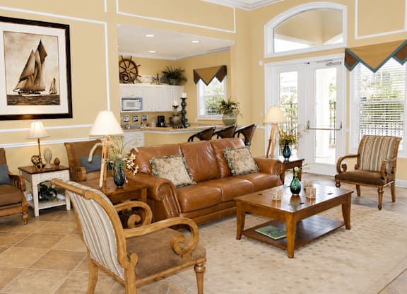 A living room with a brown couch and a painting of a sailboat on the wall.