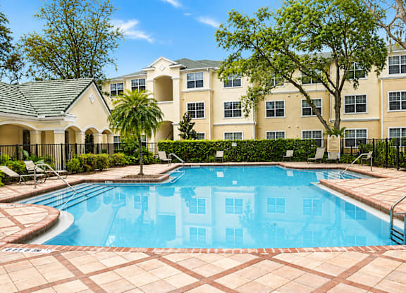 A large swimming pool in front of a building with a fence around it.
