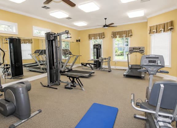 A spacious gym with a variety of equipment including treadmills, elliptical machines, and weight machines.