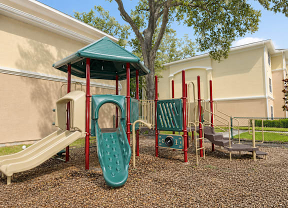 A playground with a green slide and red poles.