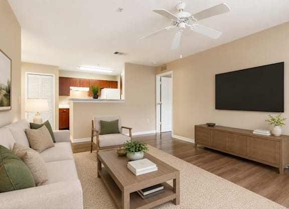 A living room with a white couch, a wooden coffee table, and a flat screen TV mounted on the wall.