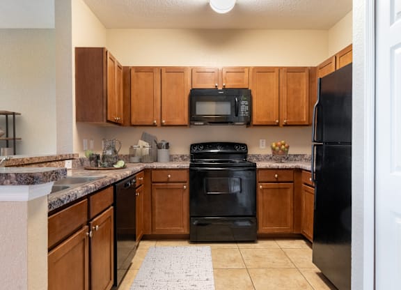 A kitchen with black appliances and wooden cabinets.
