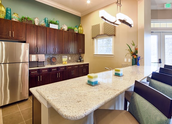 A kitchen with a granite counter top and a stainless steel refrigerator.