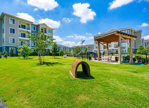 A large grassy area in front of apartment buildings with a wooden pavilion.