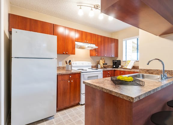A kitchen with a white refrigerator and brown cabinets.