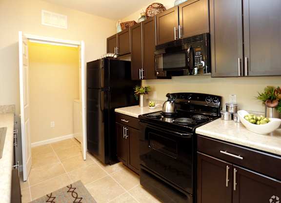 A kitchen with black appliances and brown cabinets.