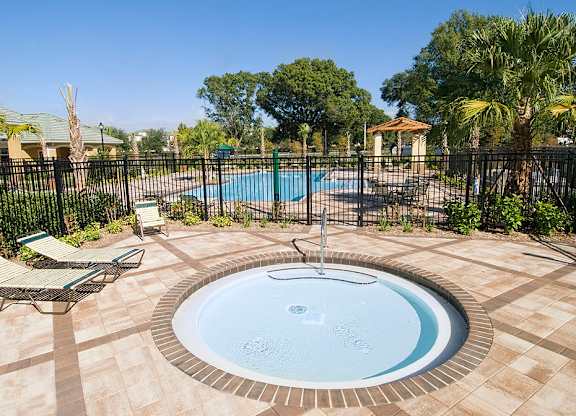 a jacuzzi in the backyard of a home with a black fence