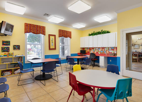 A room with tables and chairs and a television.