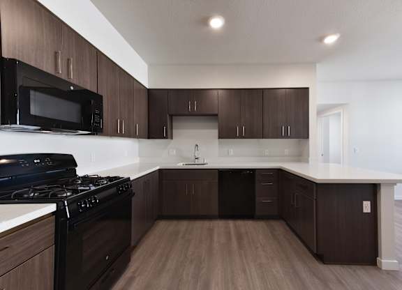 A kitchen with dark brown cabinets and a black stove top oven.