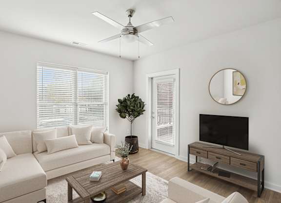 A living room with a white couch, a wooden coffee table, and a flat screen TV.