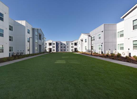 A long white building with a green lawn in front.